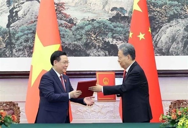 NA Chairman Vuong Dinh Hue (L) and Chairman of the Standing Committee of the National People's Congress of China Zhao Leji exchange the new cooperation agreement between the Vietnamese NA and the National People’s Congress of China. (Photo: VNA)