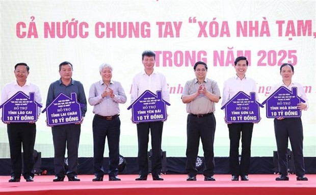 From right: Prime Minister Pham Minh Chinh (3rd) and Chairman of the Vietnam Fatherland Front Central Committee Do Van Chien (5th) hand over the tokens of funds allocated to assist in the removal of temporary and ramshackle houses across several provinces. (Photo: VNA)