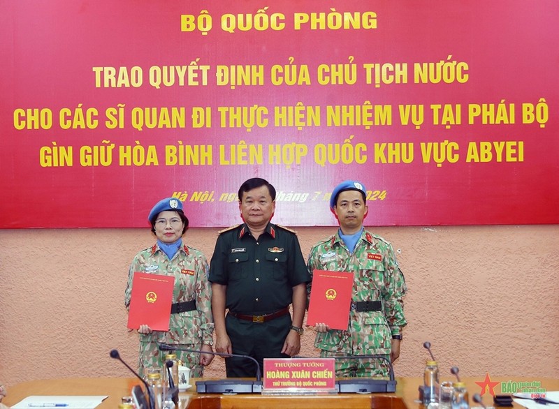 Deputy Minister of National Defence Senior Lieutenant General Hoang Xuan Chien (right) hands over the President's decision to two officers (Photo: qdnd.vn)