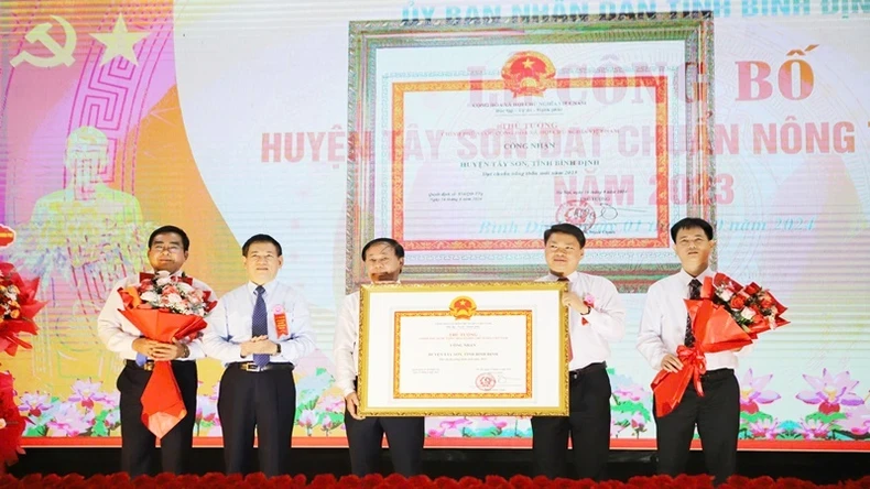 Deputy PM Ho Duc Phoc presents the Certificate of recognition of Tay Son District as a new-style rural district to the leaders of the district