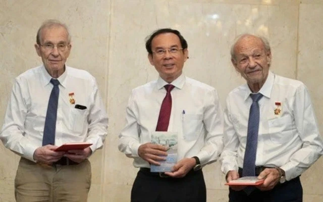 Nguyen Van Nen, Politburo member and Secretary of the Ho Chi Minh City Party Committee, presents the HCM City Badge to Olivier Parriaux and Bernard Bachelard at the meeting. 