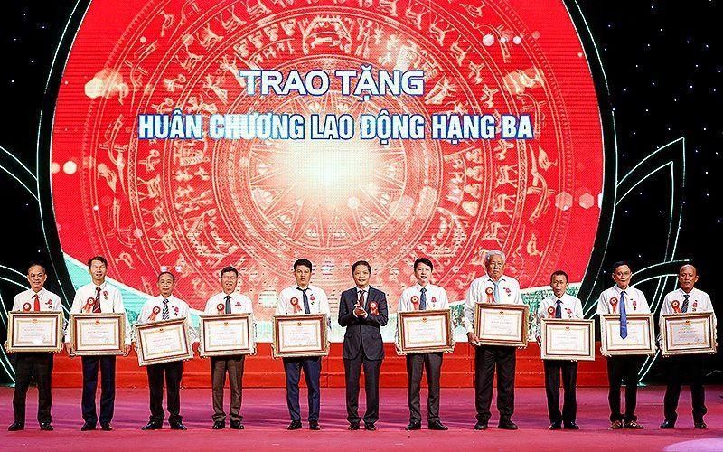 Head of the Central Economic Commission Tran Tuan Anh presents the Labour Order to ten outstanding farmers. (Photo: NDO)