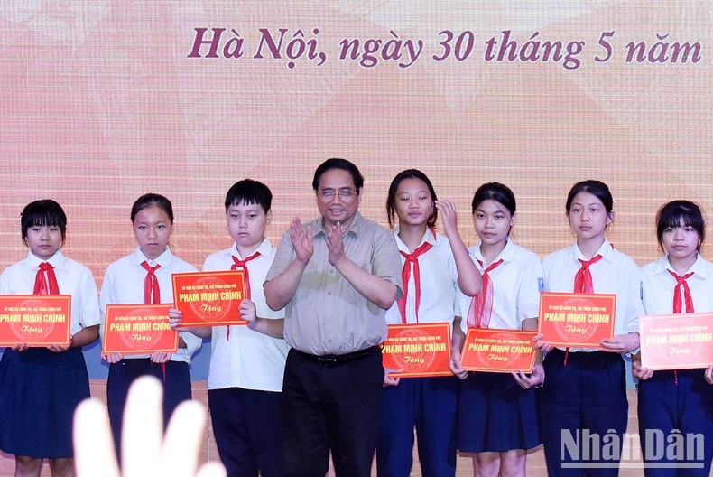 Prime Minister Pham Minh Chinh presents gifts to students of SOS Hermann Gmeiner School. (Photo: VNA) 