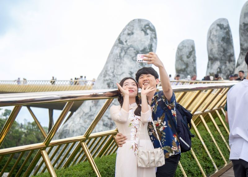 A couple takes a selfie in front of the Golden Bridge in Da Nang.
