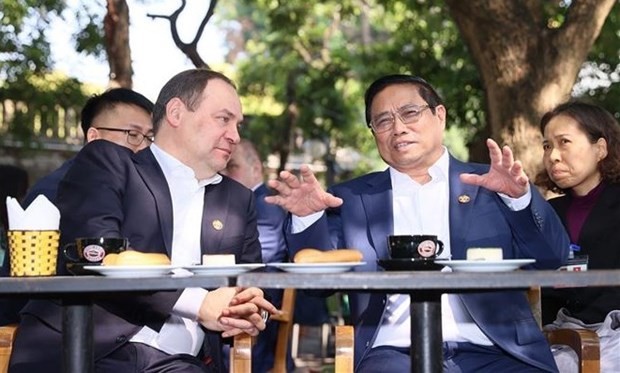 Prime Minister Pham Minh Chinh and his Belarusian counterpart Roman Golovchenko enjoy Vietnamese coffee near the Hanoi Flag Tower. (Photo: VNA)