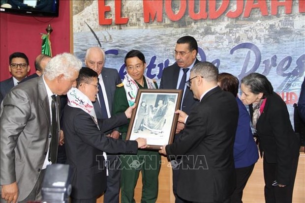 Vietnamese Ambassador to Algeria Tran Quoc Khanh (second from left) presents to General Director of El Moudjahid Brahim Takheroubt with a photo of General Vo Nguyen Giap handing over a Vietnamese flag to the Algerian Defence Minister on the occasion of his visit to the African nation in 1976. (Photo: VNA)