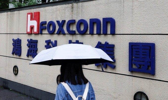 A woman carrying an umbrella walks past the logo of Foxconn outside the company's building in Taipei. (Photo: Reuters) 