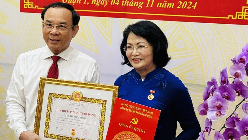 Ho Chi Minh City Party Secretary Nguyen Van Nen presents the 45-year Party membership badge to former Vice President Dang Thi Ngoc Thinh.