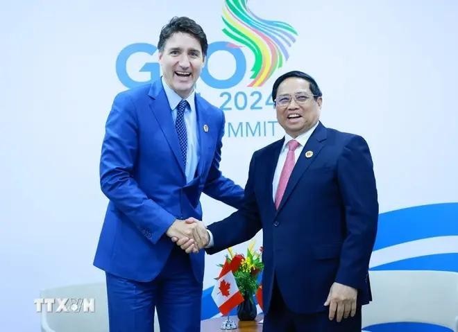 PM Pham Minh Chinh (R) shakes hands with his Canadian counterpart Justin Trudeau (Photo: VNA)