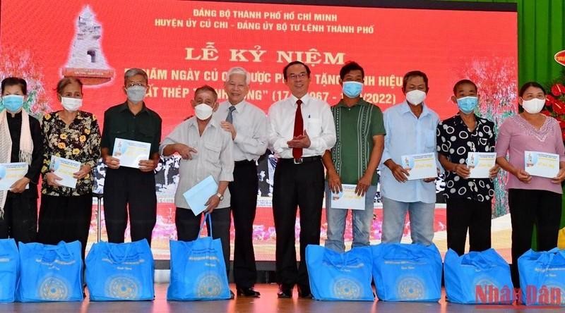 Former President Nguyen Minh Triet and Politburo member cum Secretary of the Ho Chi Minh City Party Committee Nguyen Van Nen present gifts to policy beneficiary families.