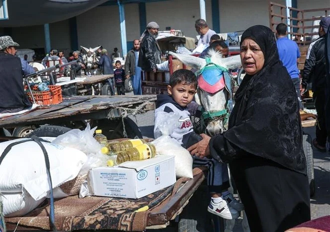 Palestinians receive food aid at a distribution centre of the United Nations Relief and Works Agency for Palestine Refugees in the Near East (UNRWA) in Rafah, Gaza Strip. (Photo: AFP/VNA)