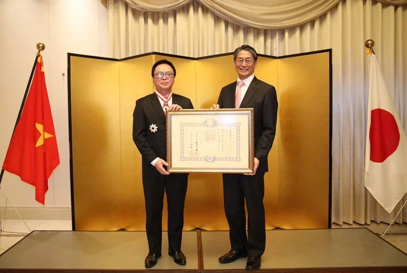 Hoang Binh Quan (left), former member of the Party Central Committee and former Chairman of its Commission for External Relations, receives the “Order of the Rising Sun, Gold and Silver Star” from Japanese Ambassador Ito Naoki on December 15.