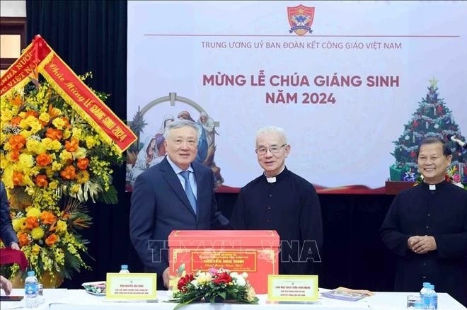 Standing Deputy Prime Minister Nguyen Hoa Binh (left) presents a X-mas gift to the Central Committee for Solidarity of Vietnamese Catholics on December 22. (Photo: VNA)