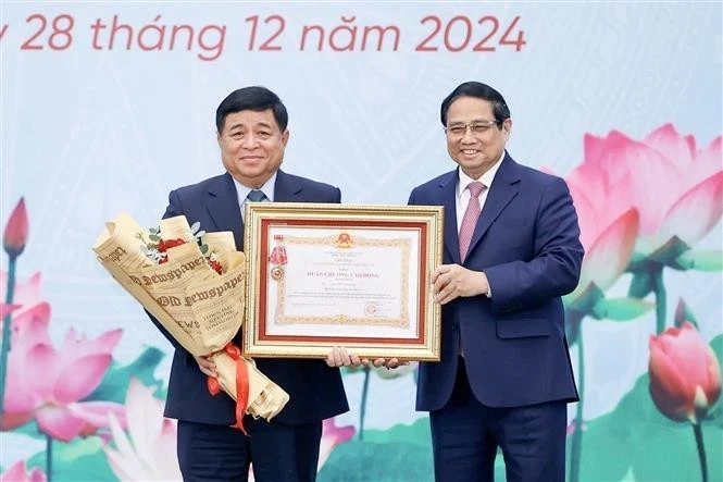 Prime Minister Pham Minh Chinh (R) present first-class Labour Order to Minister of Planning and Investment Nguyen Chi Dung (Photo: VNA)