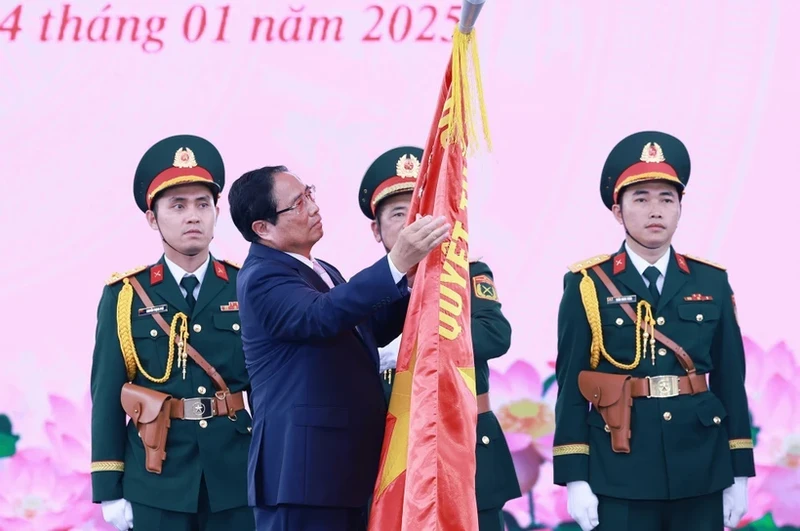 Prime Minister Pham Minh Chinh pins the token of the title of Hero of the People's Armed Forces onto the traditional flag of the Ho Chi Minh City armed forces. (Photo: VNA)