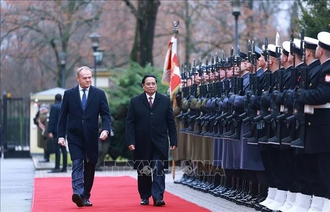 Prime Minister Pham Minh Chinh (R) and Polish Prime Minister Donald Tusk inspect the guard of honour at the welcome ceremony. (Photo: VNA)