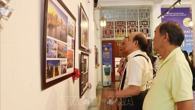 Visitors admiring photos on display at the exhibition (Photo: VNA)