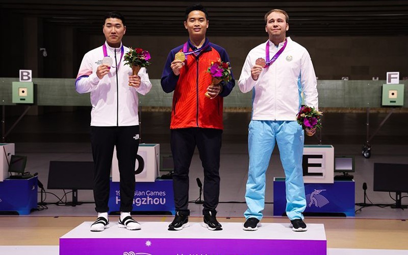 Shooter Pham Quang Huy (C) holds his gold medal in the men's 10m individual air pistol final at the 19th Asian Games. 