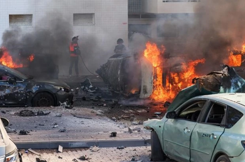 People put out fires on cars after a rocket attack from the Gaza Strip, in Ashkelon (Israel), on October 7, 2023. (Photo: AFP/VNA)