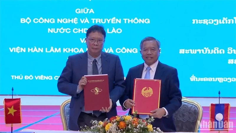 Chau Van Minh, President of the Vietnam Academy of Science and Technology (VAST) (L), and Boviengkham Vongdara, Lao Minister of Technology and Communications, exchange minutes of cooperation. (Photo: NDO/Trinh Dung)