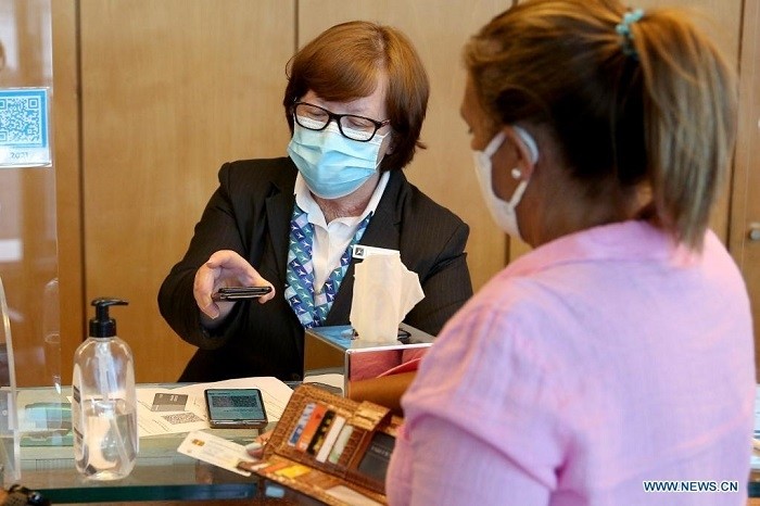 A receptionist checks a customer's COVID certificate during check-in at a hotel in Sesimbra, Portugal, on July 9, 2021. As of Friday, Portugal mandates the use of the European Union's Digital COVID Certificate or proof of a negative coronavirus test by customers at all the country's hotels and other holiday accommodation as per the decision of the Council of Ministers. (Photo: Xinhua)