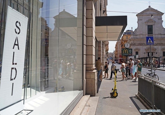 Customers line up to enter a shop with discount sign during the summer sales season in Rome, Italy, on July 3, 2021. (Illustrative Image).