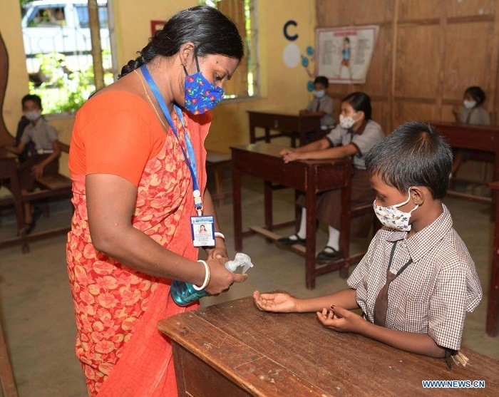 A teacher sanitizes the hands of a student at school in Agartala, the capital city of India's northeastern state of Tripura, July 27, 2021. (Str/Xinhua)