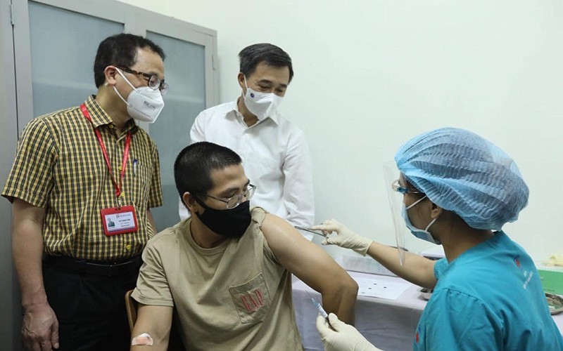 Prof. Dr. Ta Thanh Van and Prof. Dr. Tran Van Thuan witness the ARCT-154 vaccine injection for a volunteer. (Photo: Nguyen Quyet)
