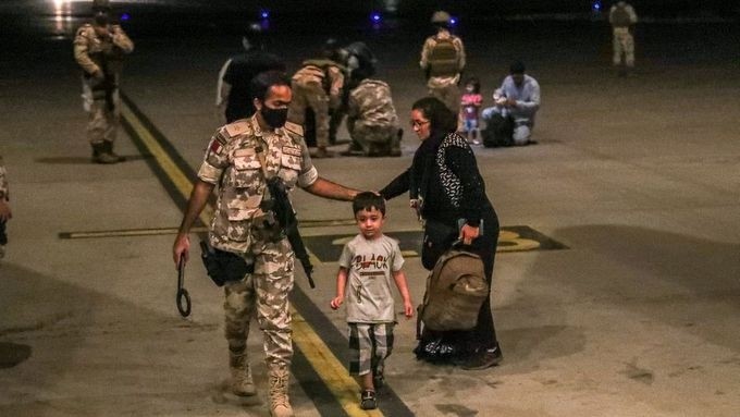 A member of the Qatar Air force walks next to a boy evacuated from Afghanistan, at Al-Udeid airbase in Doha, Qatar in this recent undated handout. (Source: Government Communications Office of the State of Qatar/Handout via REUTERS)