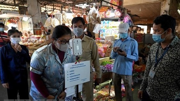 Visitors to a market in Laos have their body temperature checked. (Photo: AFP/VNA)