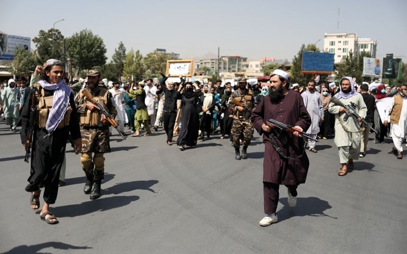 Members of the Taliban walk in front of protesters in the capital Kabul, Afghanistan, September 7. (Photo: Reuters)