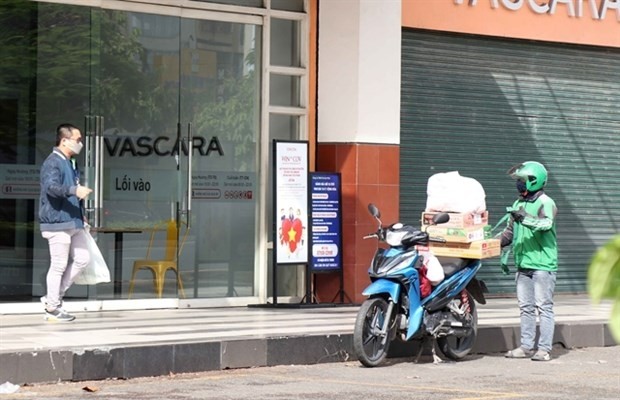 A man receives goods from a Grab delivery shipper in HCM City on July 7, 2021 (Photo: VNA)