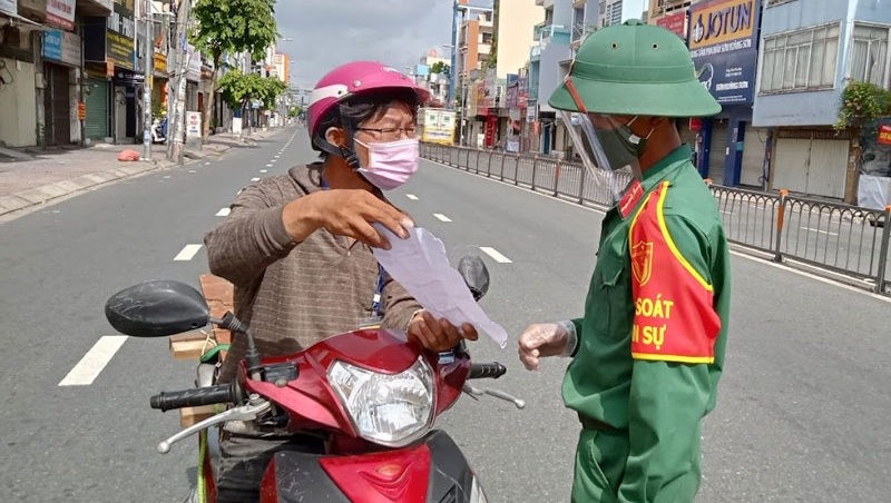 A soldier checks the travel permit of a Ho Chi Minh City resident.