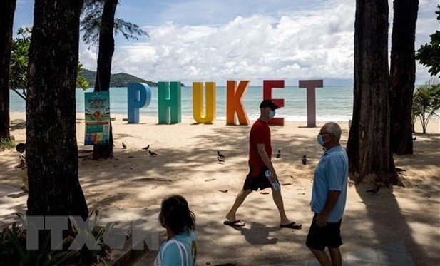 Tourists walk on the beach in Phuket, Thailand, on August 14. (Photo: AFP/VNA)
