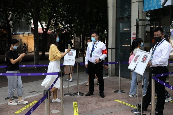 A woman shows her health status on a phone to a security guard, at an entrance of a shopping mall in Beijing, China August 23, 2021. (Photo: Reuters)