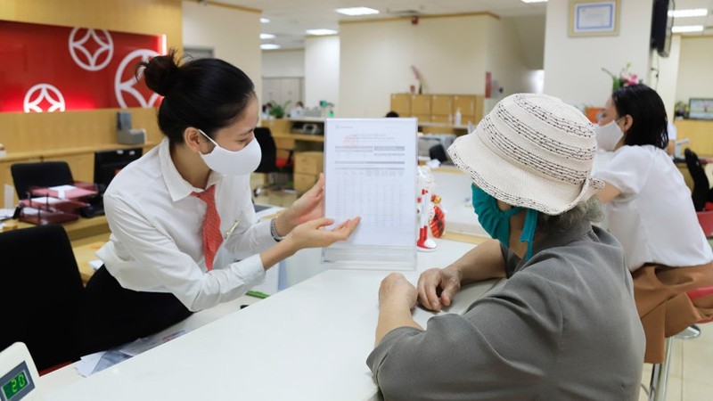 A bank teller advises a customer on savings rates. (Photo: Hanoimoi)