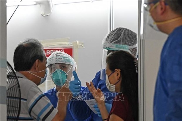 People get vaccinated against COVID-19 in Singapore. (Photo: AFP/VNA)