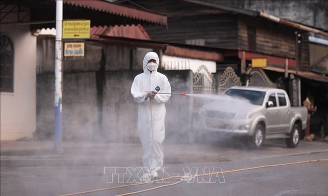 A medical staff sprays disinfectant to prevent the spread of COVID-19 in Vientiane, Laos. (Photo: Xinhua/VNA Photo)