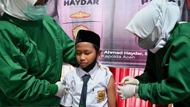 Medical staff give a student a shot of COVID-19 vaccine in Blang Bintang, Aceh province, Indonesia. (Photo: AFP/VNA)