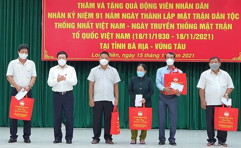 Permanent Deputy PM Pham Binh Minh presents gifts to families with outstanding achievements in patriotic emulation movements and the fight against the COVID-19 pandemic. (Photo: NDO)