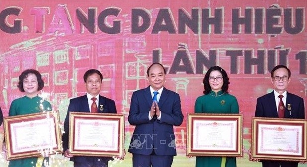 President Nguyen Xuan Phuc (centre) presents the Meritorious Teacher title to 12 lecturers of the Vietnam National University of Agriculture at the ceremony on November 20 (Photo: VNA)
