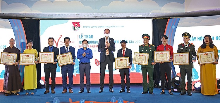 First Secretary of the Central Committee of the Ho Chi Minh Communist Youth Union Nguyen Tuan Anh and Deputy Resident Representative of the UN Development Programme (UNDP) in Vietnam Patrick Haverman (5th and 6th from left) present the National Volunteer Award 2021 to outstanding collectives and individuals.