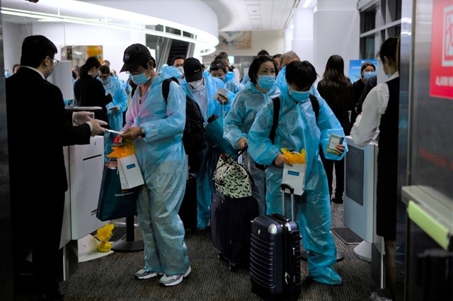 Vietnamese nationals in masks and protective clothes boarded a direct flight from the US back to Vietnam earlier in December 2021.(Photo: VNA/VNS)