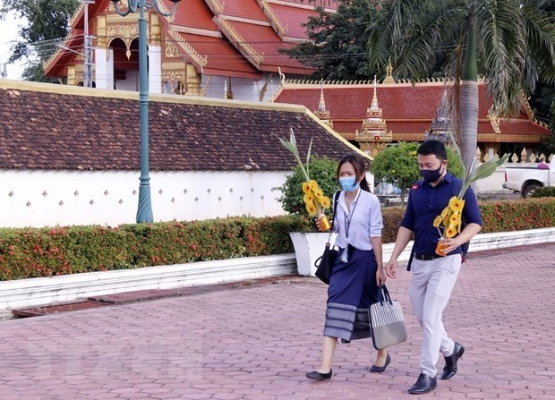 People wearing face masks are seen on a street in Vientiane, Laos. (Photo: VNA)