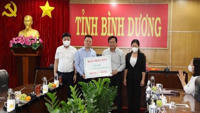Editor-in-chief of Nhan Dan Newspaper Le Quoc Minh presents 200 million VND to Binh Duong. (Photo: NDO)