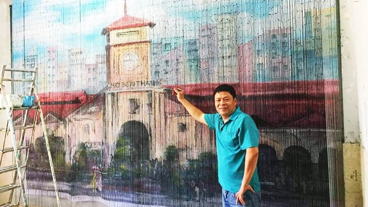 Painter Nguyen Thai Vinh and his hand-painted bamboo curtain featuring Ben Thanh Market (Photo: NDO/Le Nguyet Minh)