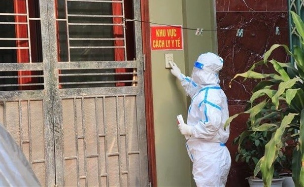 A medical staff at the door of a house with COVID-19 infected residents in the northern province of Bac Ninh to give medicine and collect samples for testing. (Photo: VNA)