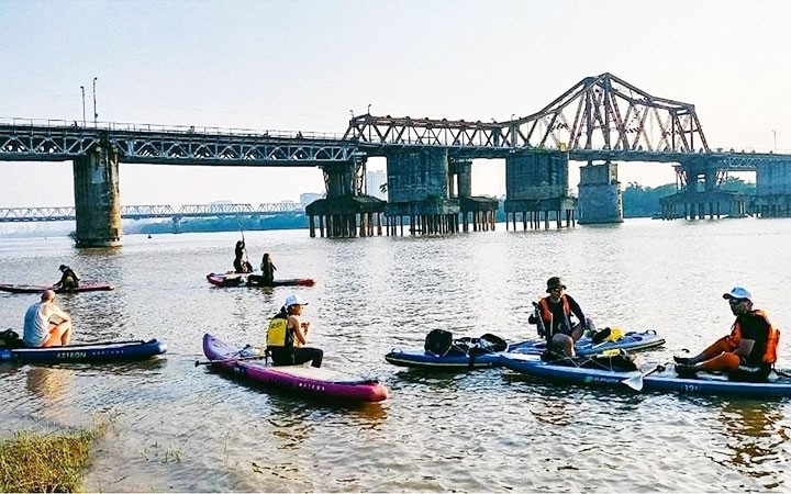 A group of tourists experiencing stand-up paddle boarding (SUP) on the Red River (Photo: NDO/Hoang My Hanh)