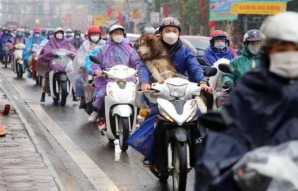 People in raincoat and warm clothes move on a street in winter. (Photo: VNA)