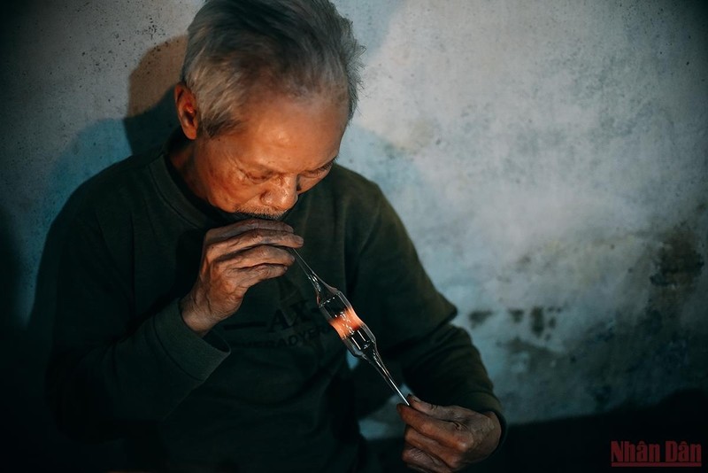 At his glass factory, Mr. Ho Van Gung (72 years old), who has been with the glass industry for more than 40 years, is producing hot batches of kerosene lamps.